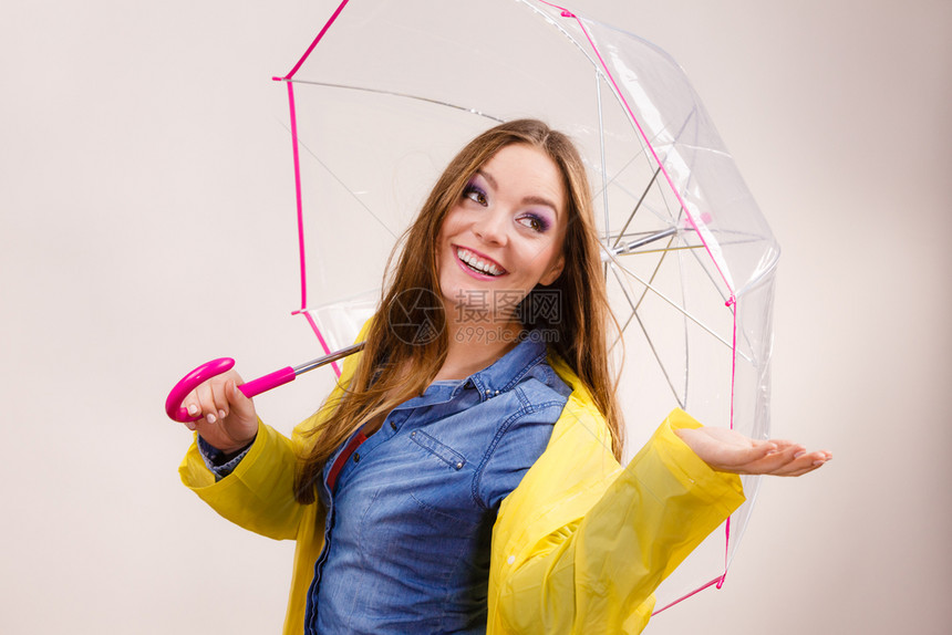 身着防水黄色大衣的女雨站在透明伞下伸展的手臂上出来捕捉雨水滴落的预测天气季节概念穿防雨大衣的女带伞预测图片