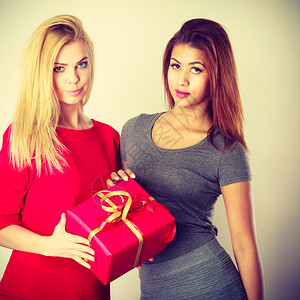 美丽的金色caucasian女孩和带红色礼品盒的Mulatto和红色礼品盒刻度图像的Mulatto背景图片