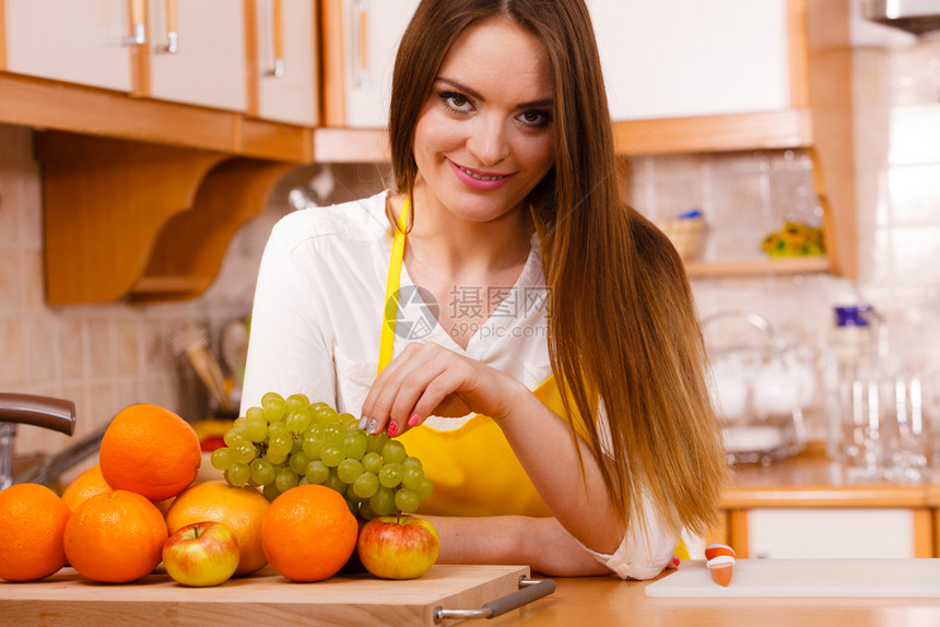 烹饪美食饮水果自然概念厨房的微笑女郎厨师靠在一堆水果和厨房用具旁边的柜台厨房微笑女郎图片