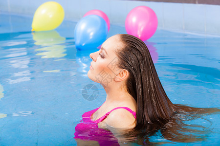 放松温泉酒店度假村概念迷人的女子在游泳池玩得开心享受水游泳池的水图片