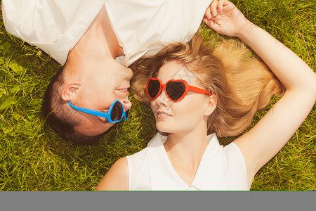 男人和女穿着心形太阳镜躺在草地上看着快乐图片