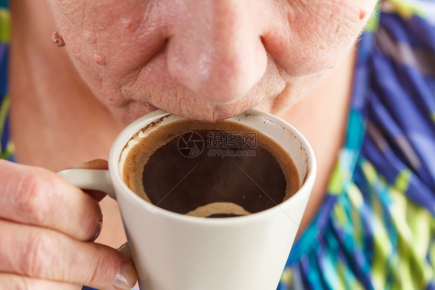 老年妇女在家里喝热饮老年领取养恤金的妇女手里握着咖啡杯老年妇女喝咖啡图片