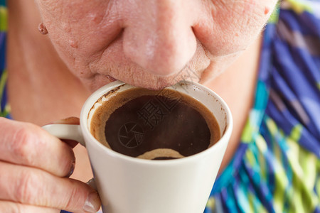老年妇女在家里喝热饮老年领取养恤金的妇女手里握着咖啡杯老年妇女喝咖啡图片