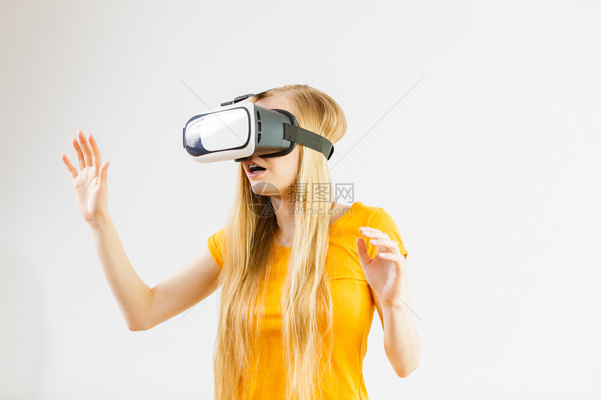 年轻女身着虚拟现实戴的护目镜头盔软箱伸展臂连接技术新一代和进步概念工作室拍摄灰色女孩身着虚拟现实戴的护目镜图片