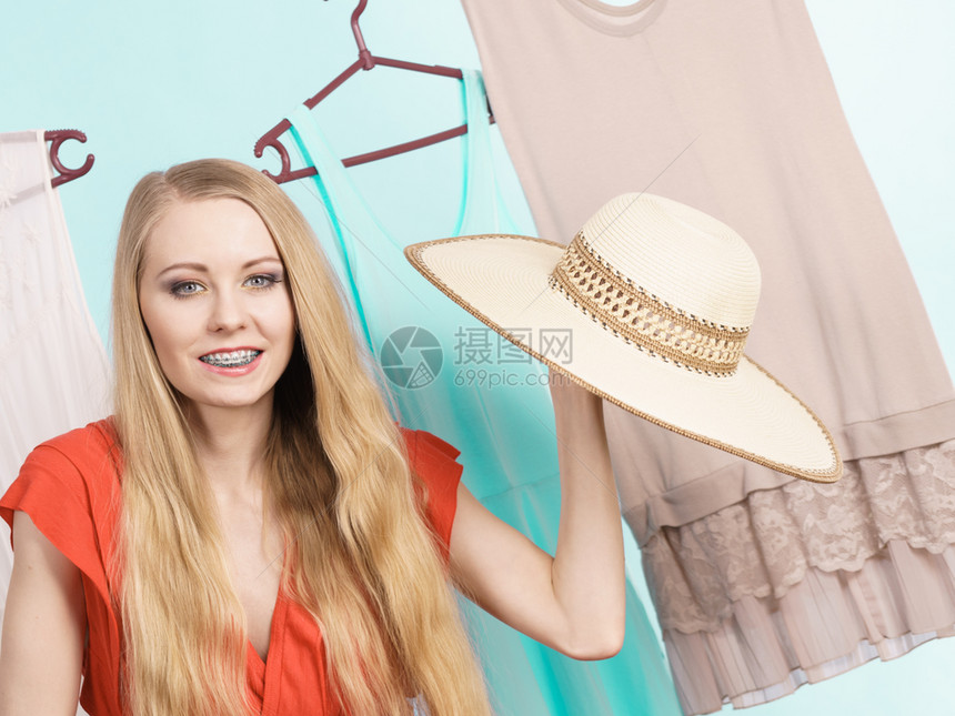 穿衣服的店铺里女人挑出完美的夏天服装拿着大帽子穿挂在衣服架上的穿着蓝色图片