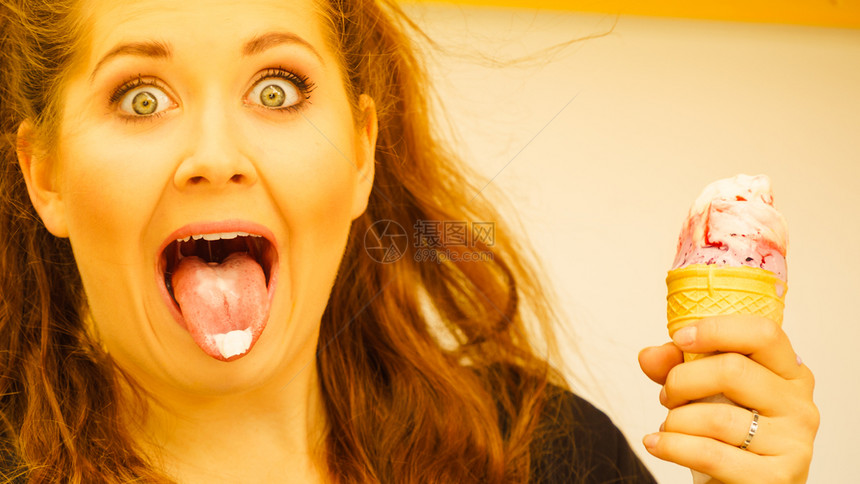 快乐的笑惊喜年轻女人长棕色头发吃冰淇淋玩得开心惊吓的女人看着冰淇淋图片