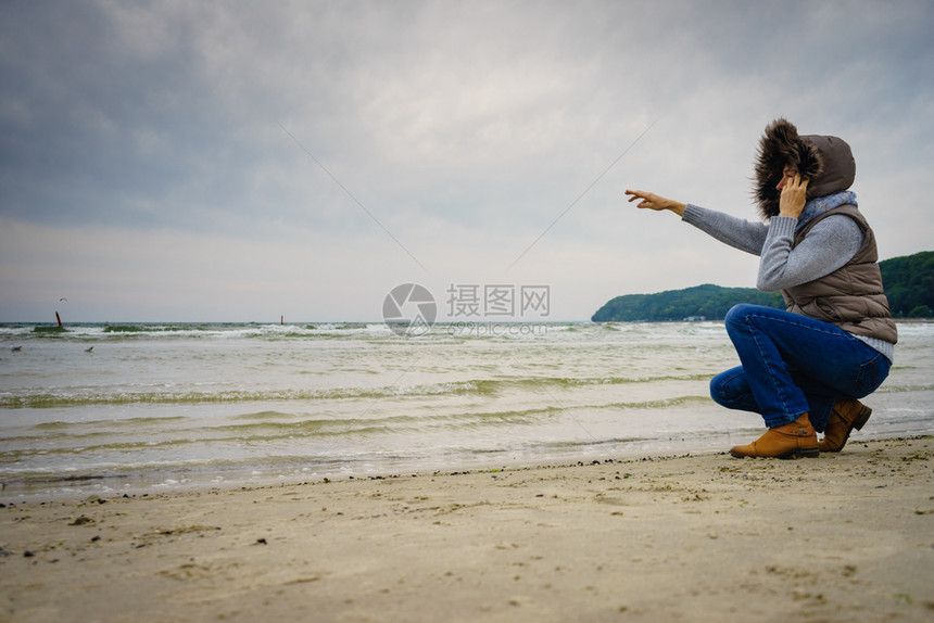 休闲和在海滩上行走的妇女在自然中与水位相近的女旅游者秋寒季日在大自然中与水站相近的女旅游者秋冬季在冷日图片