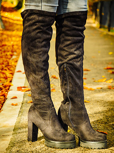 穿着长的黑脚靴高子和牛仔裤秋色时装温暖鞋靴的妇女图片