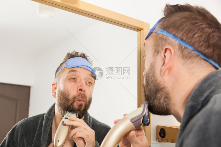胡子人用电动刮刀子用镜中长的胡子涂着困睡眼罩的照顾面部头发人剃胡子修剪他胡子图片