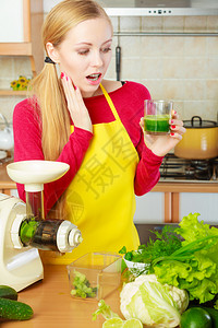 厨房里拿着绿色健康蔬菜果汁杯的惊吓女青年厨房里拿着蔬菜果汁的女子图片