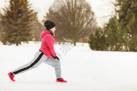 年轻的女孩冬天穿着羽绒服在雪地上锻炼身体图片