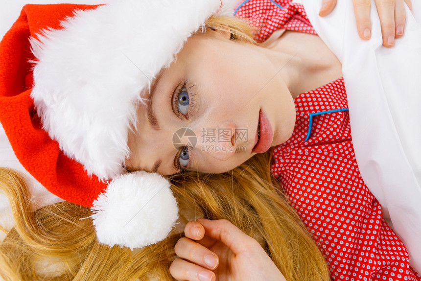 快乐的女士在等待圣诞节穿着睡衣和圣诞老人的帽子躺在床上快乐的女士穿着睡衣和圣诞老人的帽子图片
