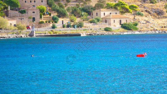 在阳光明媚的夏季天气中蓝水和海岸线旁边有浮标的蓝水图片