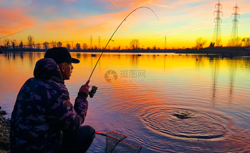 日落时在池塘捕鱼的渔夫图片