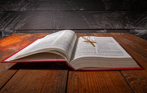 书张开的书张开的圣经上面有红色的罩子还有一小块金属在旧的黑木质表面的铁链上背景