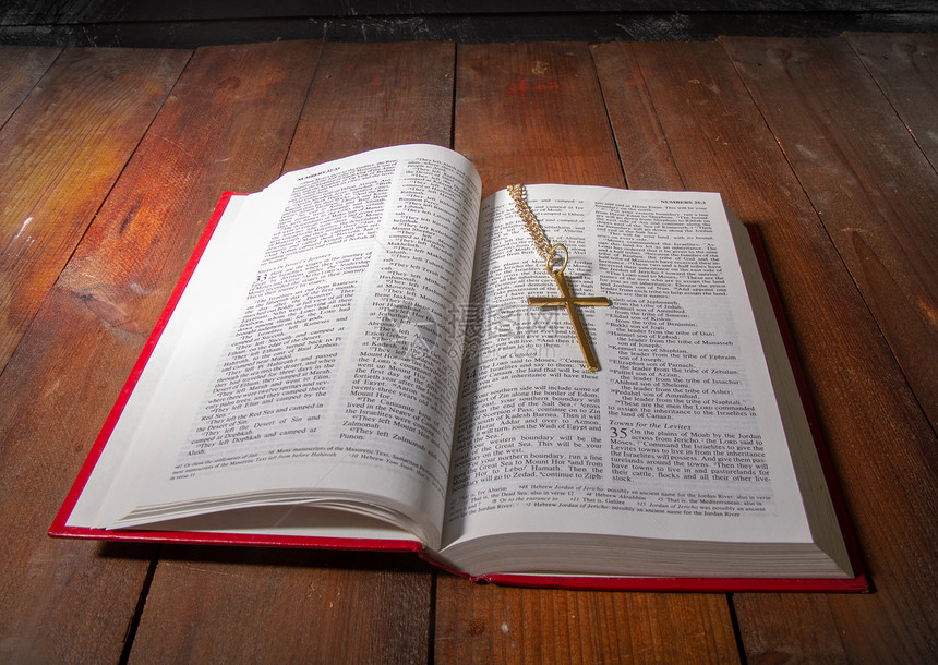 张开的圣经上面有红色的罩子还有一小块金属在旧的黑木质表面的铁链上图片