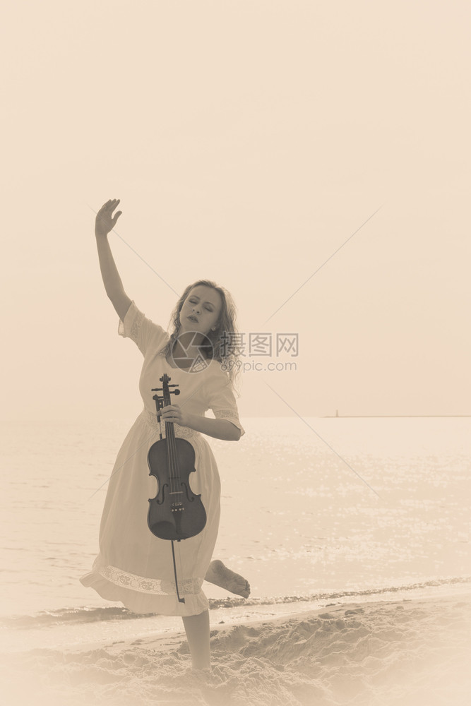 音乐爱好和日常激情概念海边滩上的妇女拿着小提琴海边滩上的妇女拿着小提琴海边的妇女拿着小提琴图片