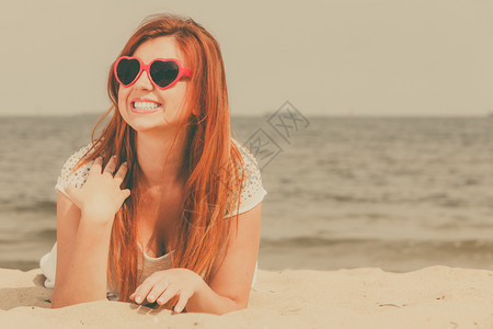 快乐的红发成年妇女夏天躺在沙滩上红发成年妇女躺在沙滩上背景图片