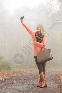 雾炮机秋天公园的时装女郎拍了自照片穿着毛衣的欢乐少女穿着毛衣手提包照片背景
