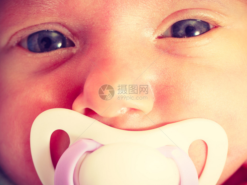 婴儿护理童年概念的美丽小新生婴儿平静地躺在床上嘴里塞着小茶叶闭合图片