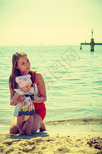 母亲和女婴在靠近海边的滩上度过时间图片