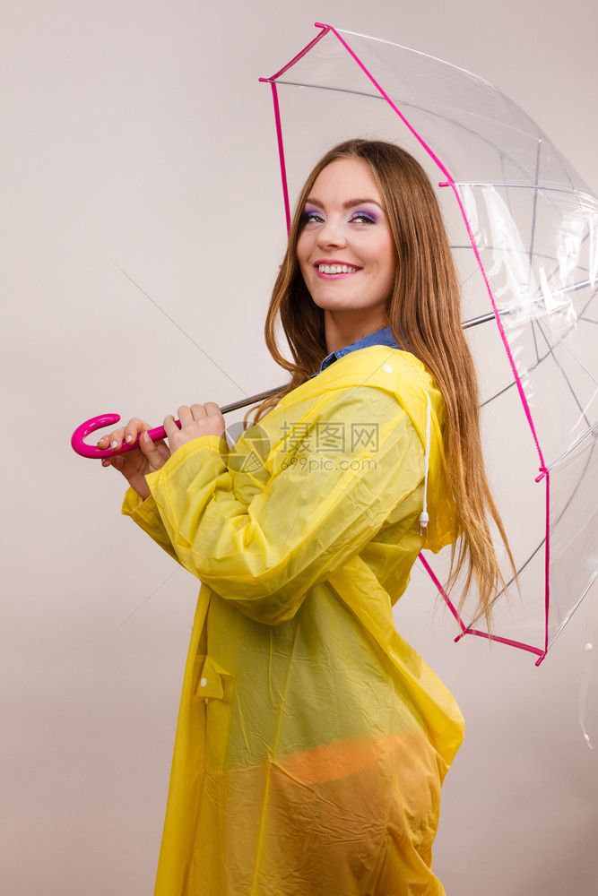 身着防水黄色大衣站在雨伞下玩得开心的雨中微笑女孩气象预报和天季节概念身着雨伞下防水大衣的妇女图片