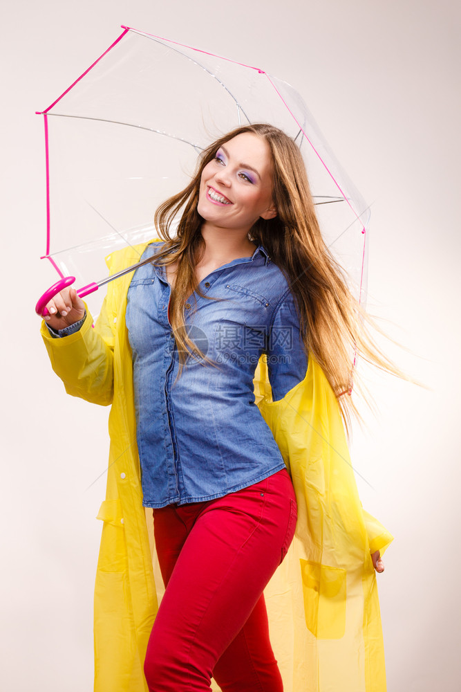 身着防水黄色大衣站在雨伞下玩得开心的雨中微笑女孩气象预报和天季节概念身着雨伞下防水大衣的妇女图片