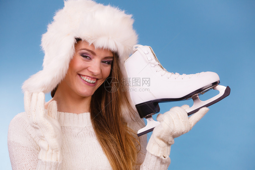 有冰鞋的女人准备去滑冰冬季体育活动穿着温暖衣服毛和帽的微笑女孩在蓝工作室拍摄带冰鞋的女人准备去滑冰图片