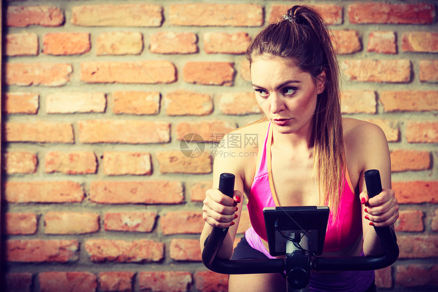 在健身房使用健身自行车瘦身减肥的女士图片