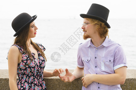 男女在海边戴着Fedora的帽子享受浪漫的约会图片