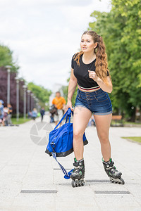 身穿溜冰鞋手持运动袋的青年女子在城里骑马图片