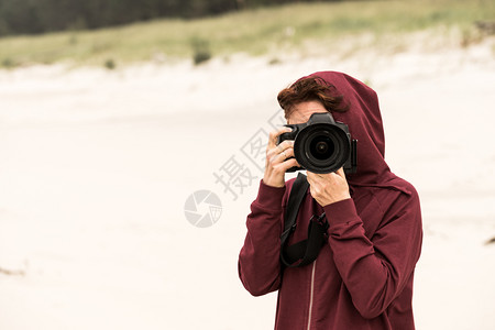 在秋天的气下妇女闲暇时间在海岸线上走动用照相机拍图片