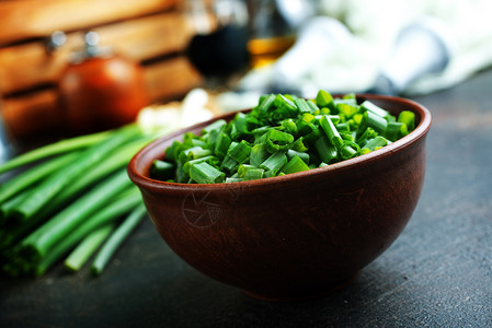 厨房桌上的绿洋葱新鲜和刀图片