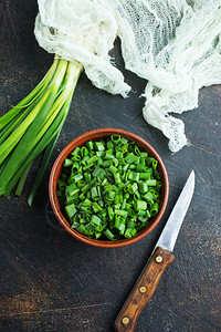 厨房桌上的绿洋葱新鲜和刀图片
