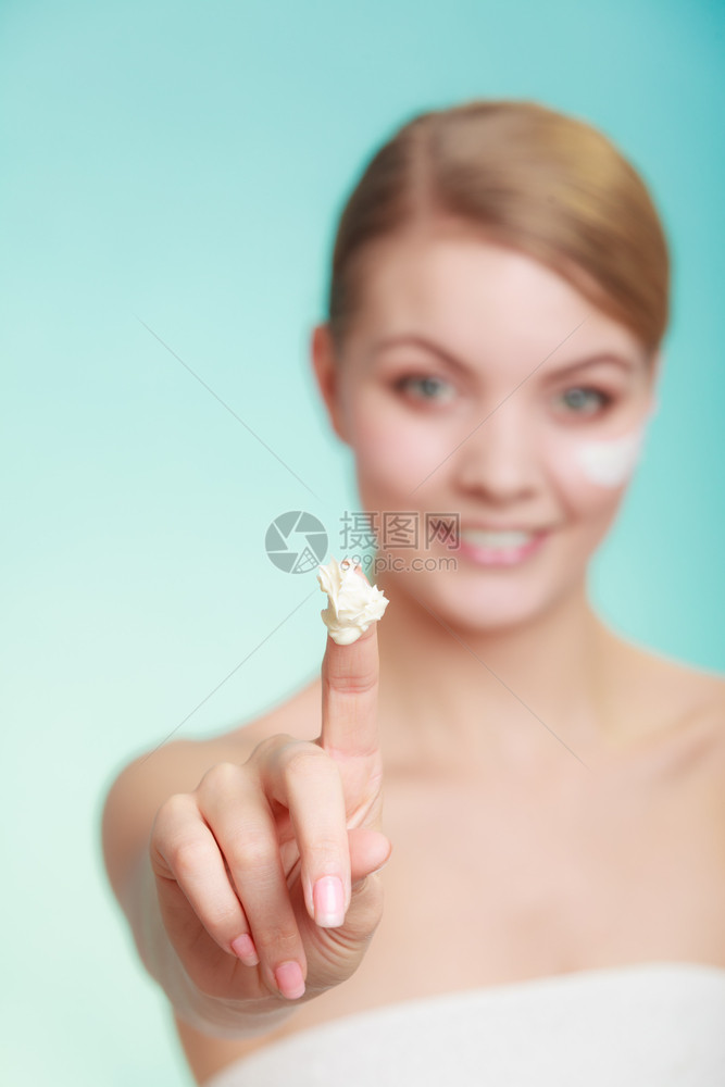 美容治疗女在脸部工作室使用湿润的奶油护肤产品在绿蓝背景下拍摄女在皮肤上涂奶油图片