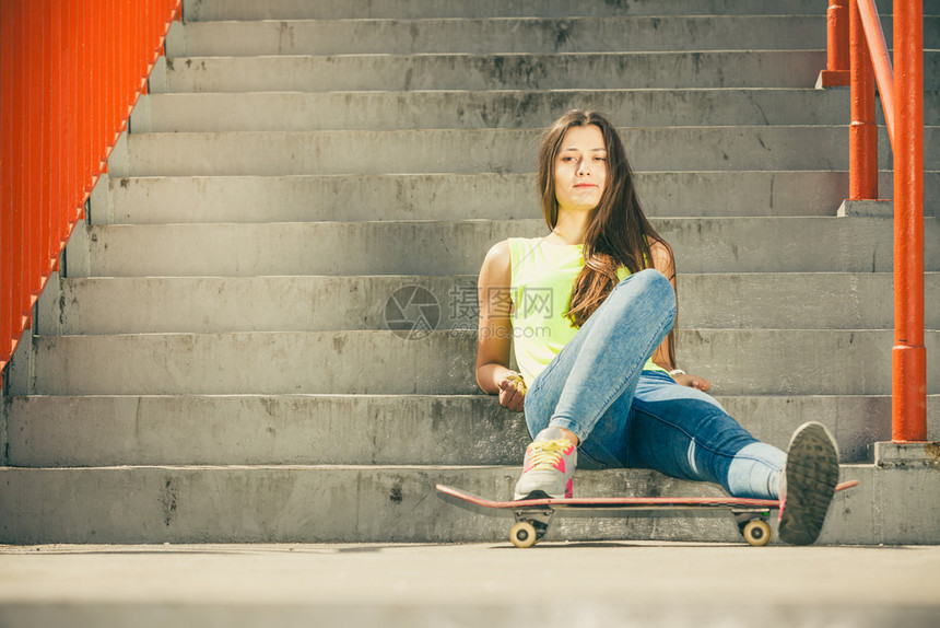 酷的长发女孩坐在城市的楼梯上滑板坐在城市的楼梯上夏季的活跃生方式很滑稽特伦迪运动青少年带滑板的在楼梯上女孩图片