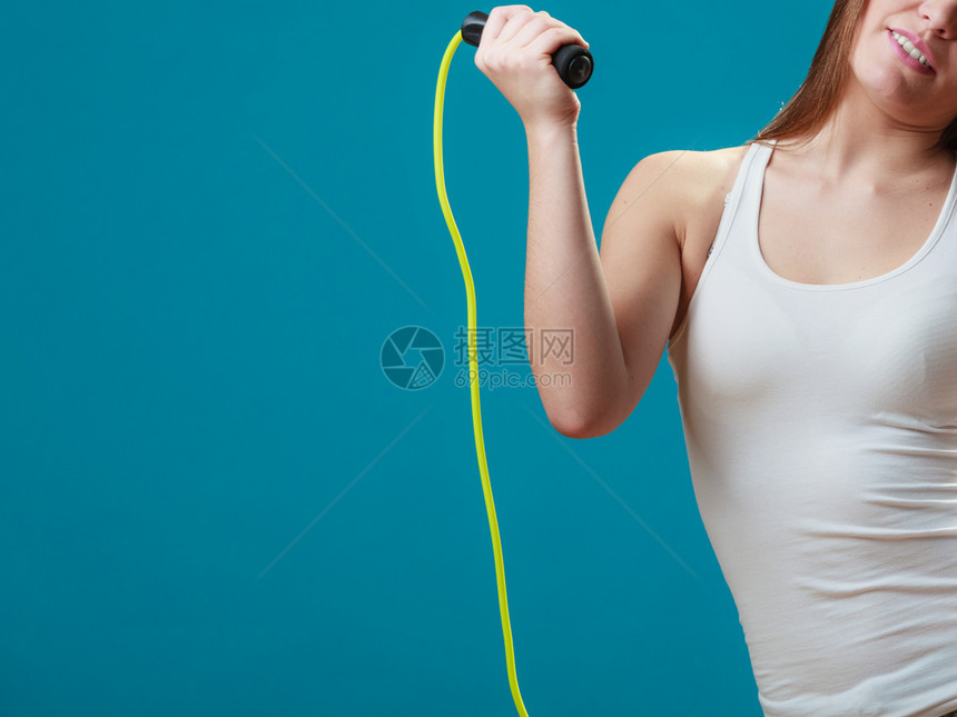 身穿运动服的女孩在蓝背景上跳过绳子图片