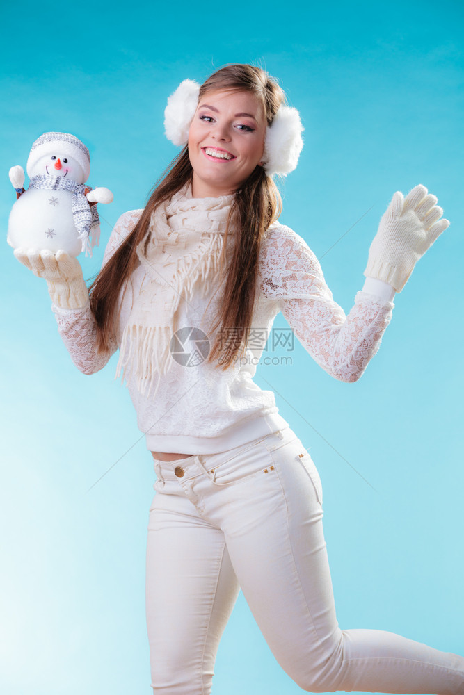 穿着温暖衣服的年轻女孩带着快乐的雪人玩具图片