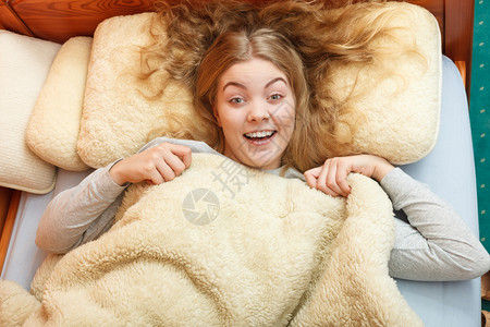 年轻女孩躺在羊毛毯下妇女睡觉后早上在床醒来图片