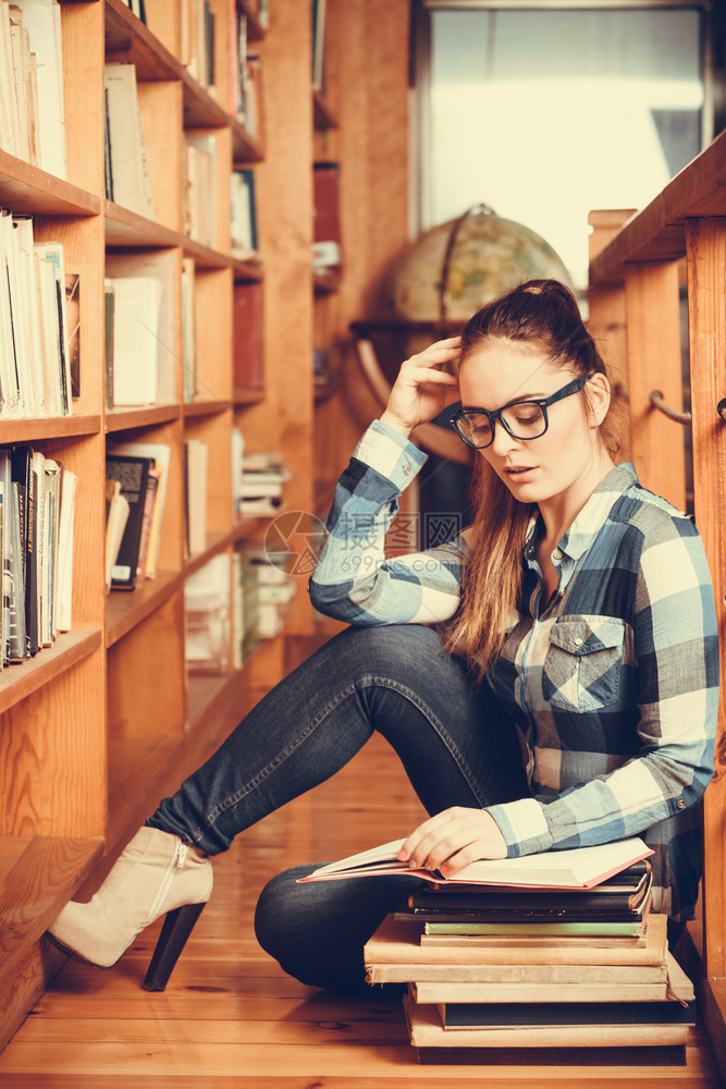 教育学校概念聪明的女学生毛发马尾小女孩眼镜坐在有书本的大学图馆地板上图片