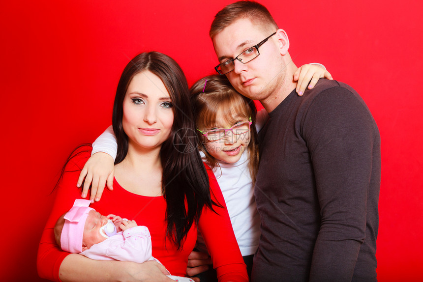 托德勒女孩父亲和母抱着睡觉的新生儿婴红色背景托德勒女孩父亲和母抱着新生儿图片