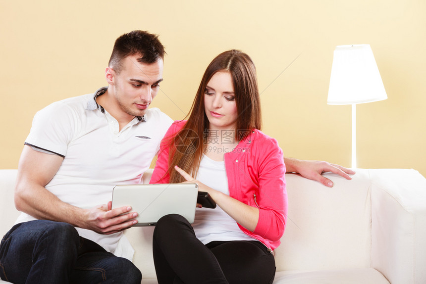 两人在网上购物平板电脑两人在家中沙发上使用新技术冲浪互联网图片