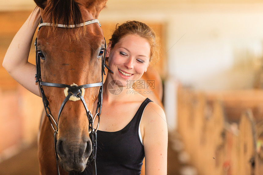 骑马的年轻女孩抚摸和拥抱着稳定的棕色马骑年轻女孩抚摸和拥抱着棕色马图片