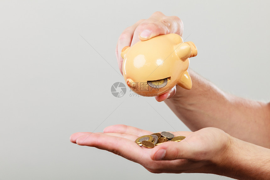 花钱概念男人手笔储蓄硬币和小猪银行手图片