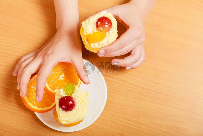 女手拿甜食饼干蛋糕奶油和水果作为甜点食物上面配橙子盘上加手拿美食奶油蛋糕饼干和橙子图片