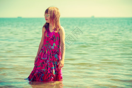 穿着夏衣步行和在水中玩的年轻女孩穿着衣服的托德勒女孩在水中玩图片