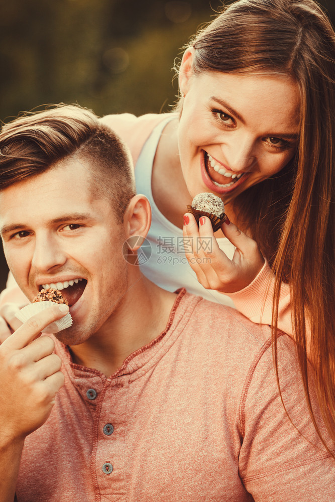 爱与幸福可的情侣吃蛋糕饼干微笑着在公园花里吃甜食的人图片