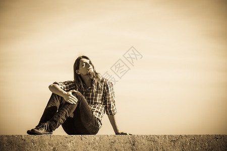 在阳光明媚的白天坐在水泥墙上与天空对图片