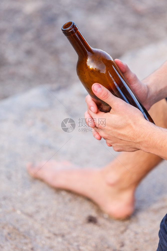 男人在户外海边喝着葡萄酒瓶子的情绪低落,人们和酗酒问题,男性与瓶子在户外图片