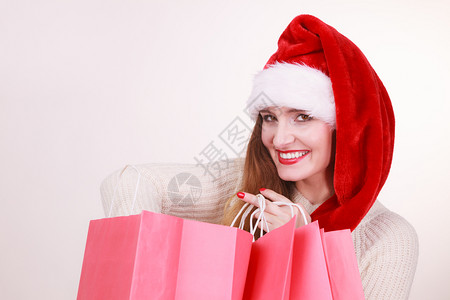 圣诞时间戴克劳斯帽子拿着红色购物袋买礼的年轻拉丁女人图片